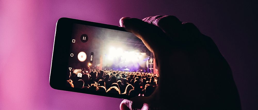 Eine Person filmt ein Konzert mit einem Mobiltelefon.